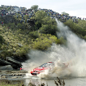 a rally car splashing trhough a big puddle