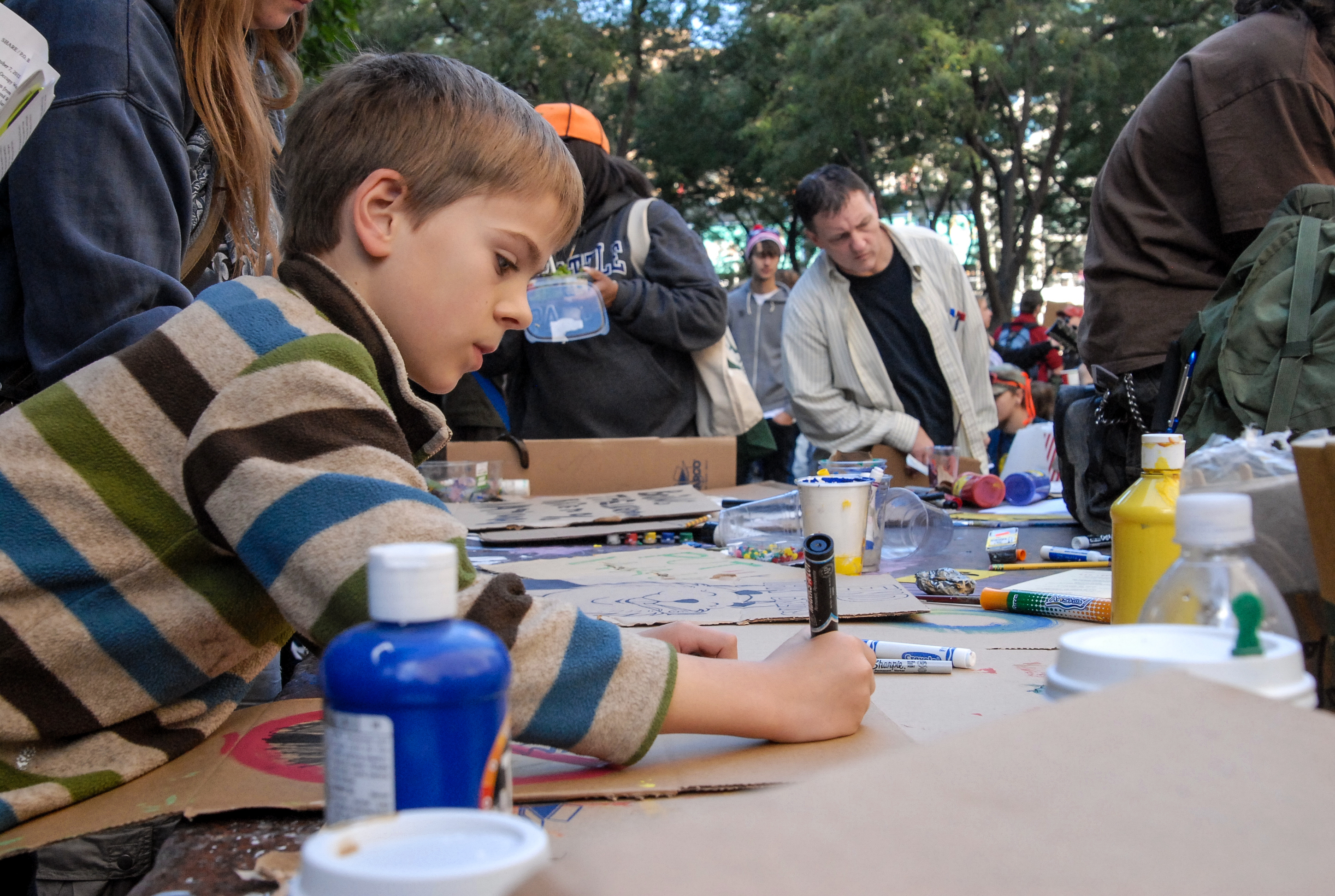 A young Occupy protestor crafts his sign.<br />10/08/2011 @ 13:54<br />Camera: NIKON D200<br />Lens: Tamron SP AF 28-75mm f/2.8 XR Di LD Aspherical (IF) Macro (A09)