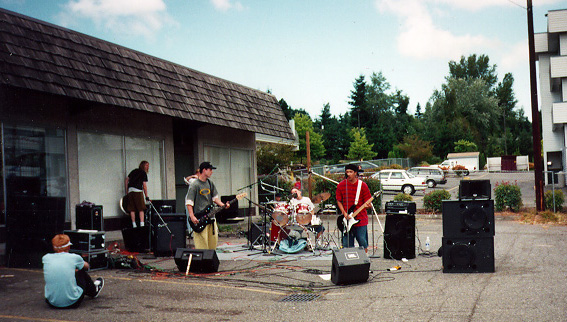 the band playing a show in the parking lot of a skateshop